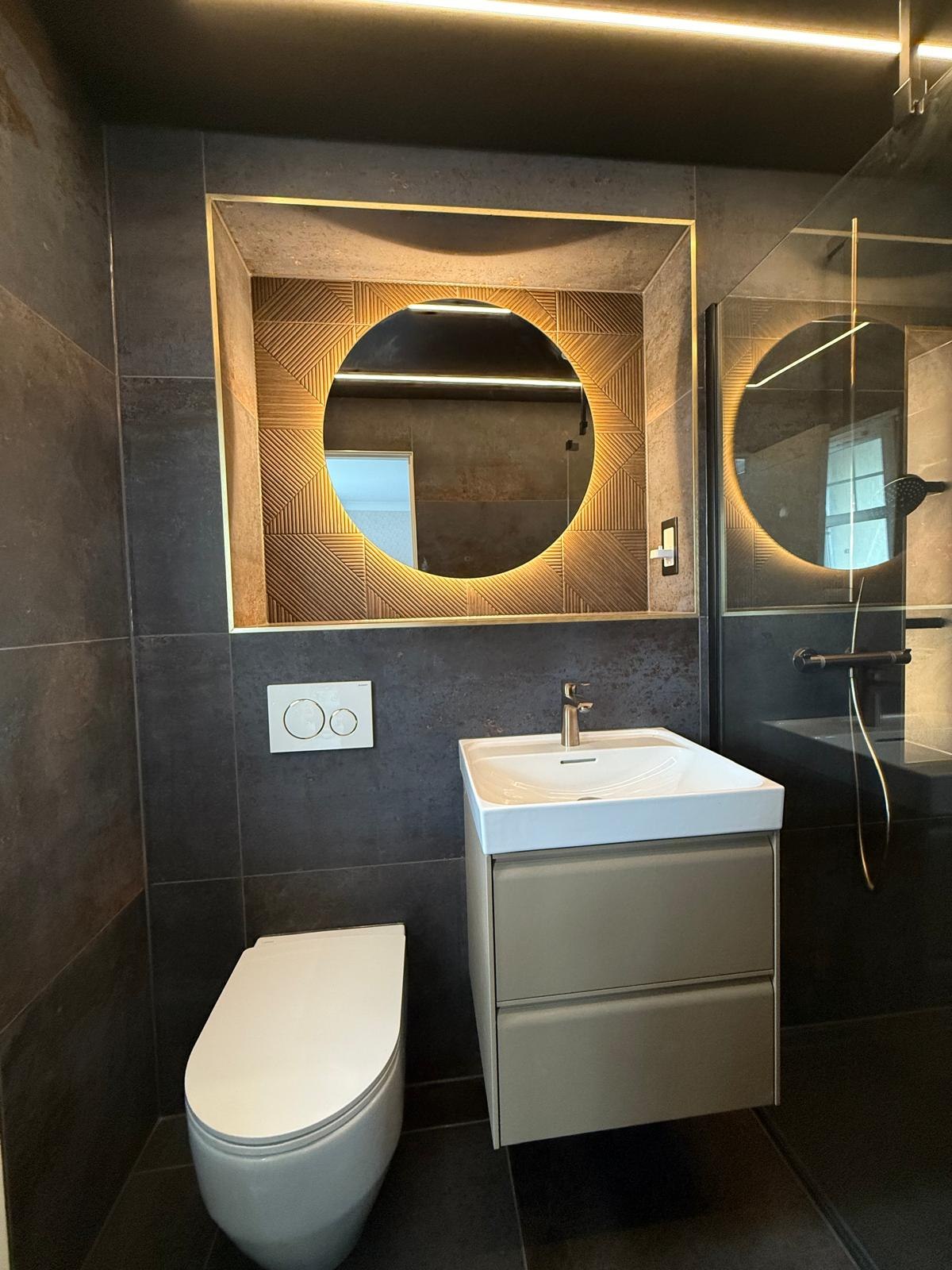 Charcoal en-suite with backlit round mirror in gold-lit textured recess