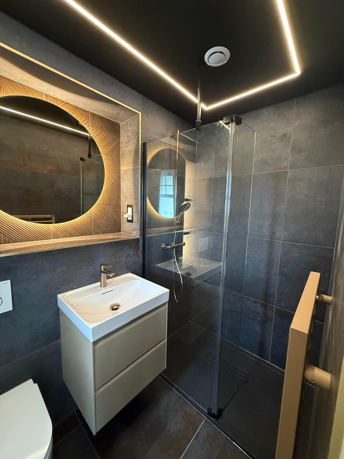 Walk-in shower with charcoal tiling and illuminated feature mirror recess